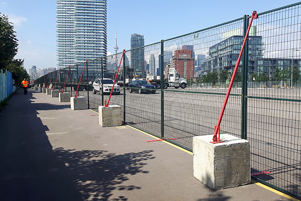 Concrete blocks and wind braces help stabilize temporary fence