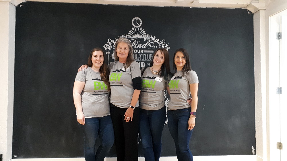 A group photo of four women wearing Building Women t-shirts